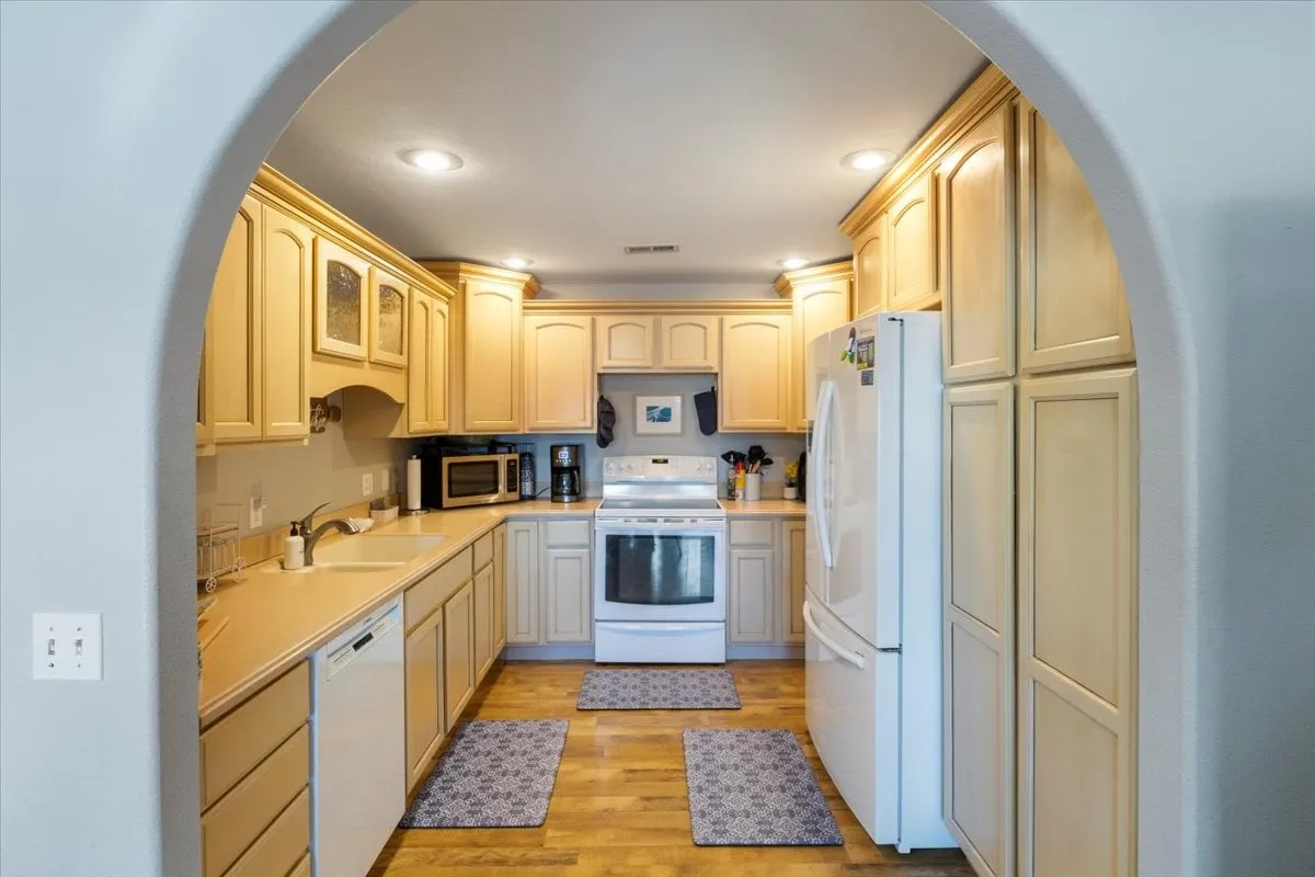A welcoming kitchen space featuring cabinetry, a stove, sink, and refrigerator, with plenty of counter space visible for meal preparation. The layout hints at a family-friendly, functional kitchen designed for group cooking or casual meals together.