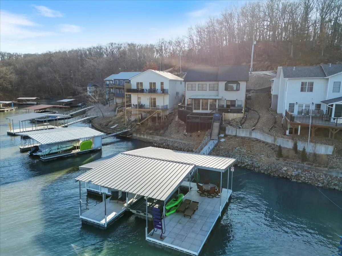 A wide exterior shot showing boathouses, docks, kayaks, the lake, and surrounding forest. This angle emphasizes the property’s lakeside position and the range of water activities available, from kayaking and fishing to simply enjoying the tranquil environment.