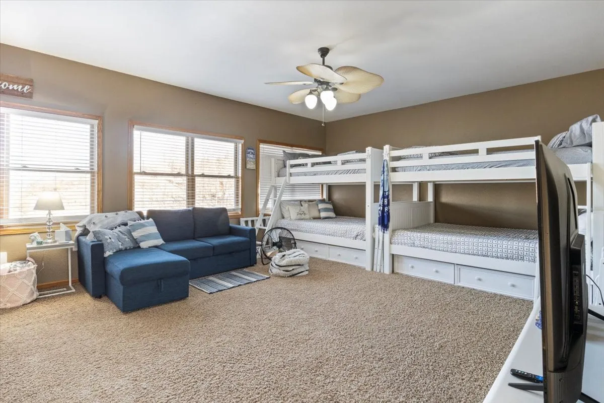 A spacious room with bunk beds, a sofa, and large windows letting in natural light. This cheerful, family-friendly sleeping area is ideal for children or groups, offering both relaxation and play spaces.