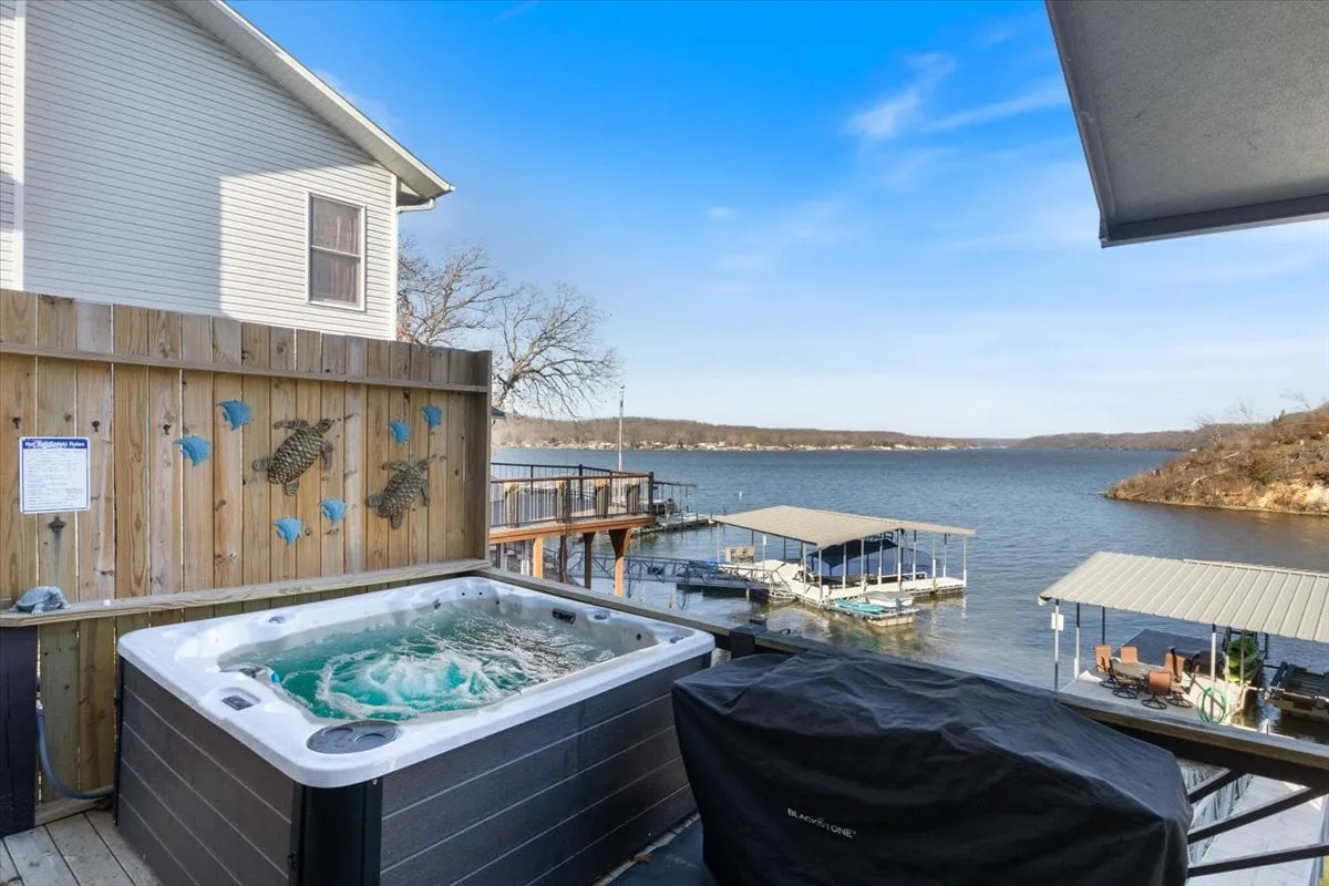 This image presents a relaxing hot tub positioned on an upper deck with a sweeping water view, perfectly embodying the lakeside spa atmosphere described in the section. The deck area is visible, suggesting space for socializing and enjoying the outdoors.